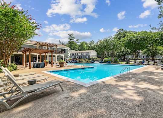 A pool area with sun loungers and a building in the background.