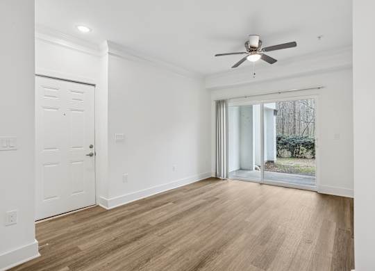 A room with a ceiling fan and sliding glass doors.