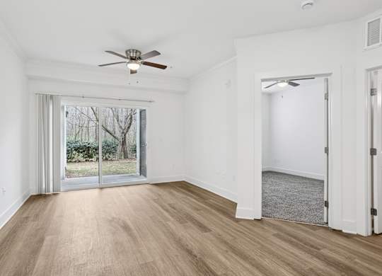 A room with a ceiling fan and sliding glass doors.