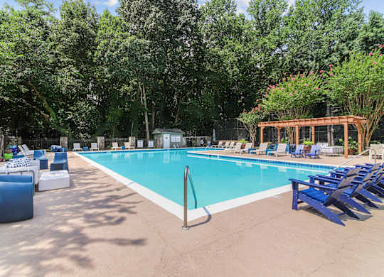 A large swimming pool surrounded by trees and lounge chairs.