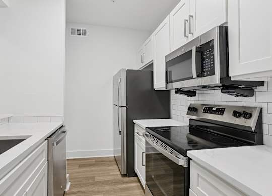 A kitchen with white cabinets and black appliances.
