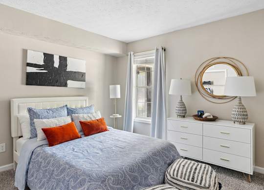 A bedroom with a bed, nightstand, and a painting on the wall.