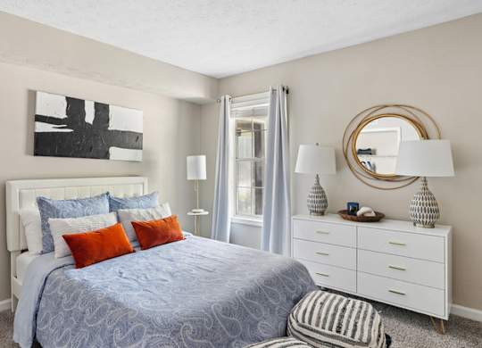 A bedroom with a bed, nightstand, and a mirror.