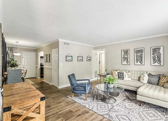 A living room with a couch, chairs, and pictures on the wall.