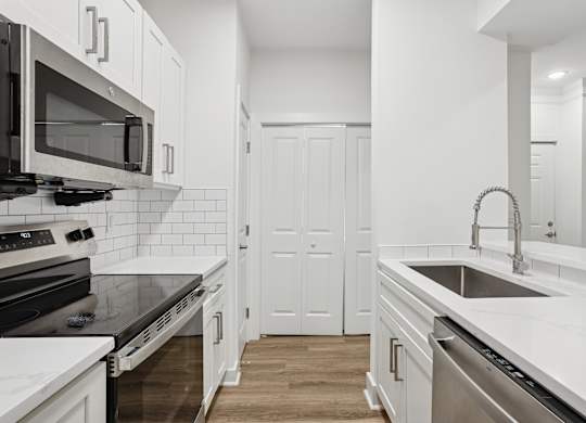 A kitchen with white cabinets and a black countertop.
