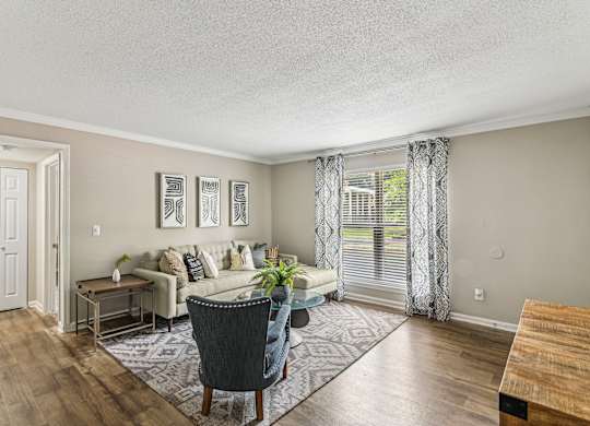 A living room with a couch, chair, and pictures on the wall.