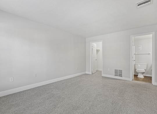 A white room with a carpeted floor and a toilet in the corner.