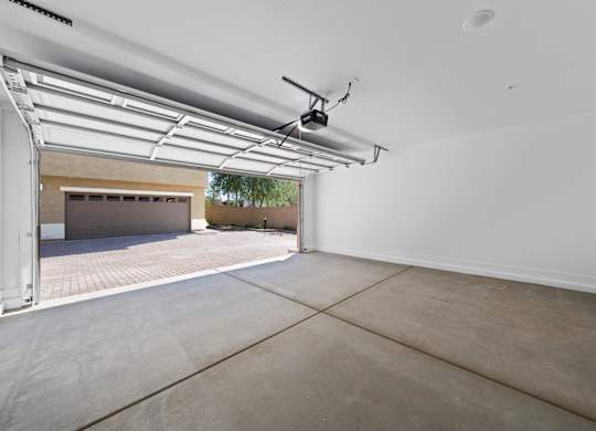 A spacious garage with a concrete floor and a ceiling fan.