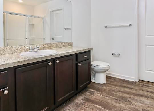 A white toilet sits in a bathroom with dark wood cabinets.