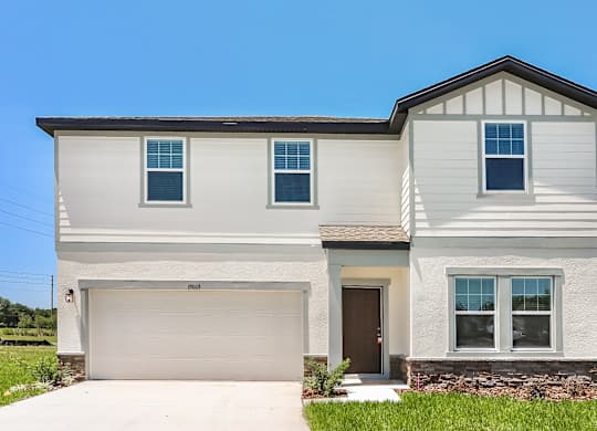 A two-story house with a garage and a brown door.