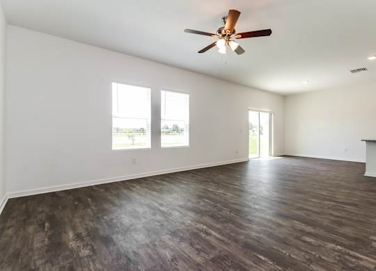 A room with a ceiling fan and wooden flooring.