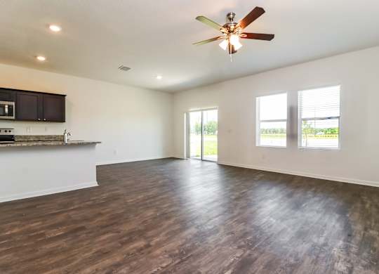 A spacious room with a ceiling fan and wooden flooring.