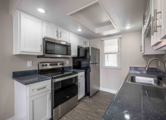 a kitchen with white cabinets and black counter tops