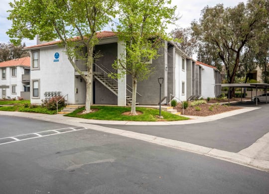 the street in front of an apartment building with trees