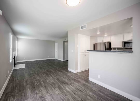 a renovated living room and kitchen with white walls and wood floors