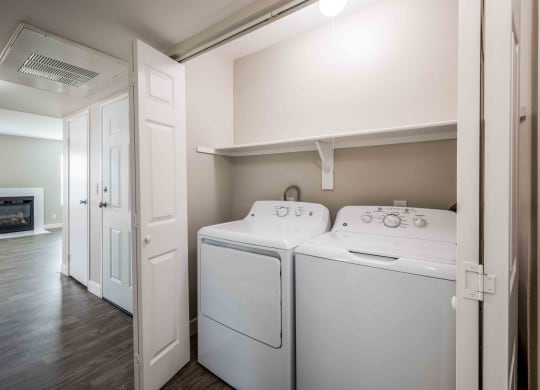 Pet-Friendly Apartments In Moreno Valley, CA - Sorelle Apartments - Laundry Closet with In-Home Washer and Dryer, Storage Shelf, and Folding Door.