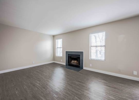 an empty living room with a fireplace and wooden floors
