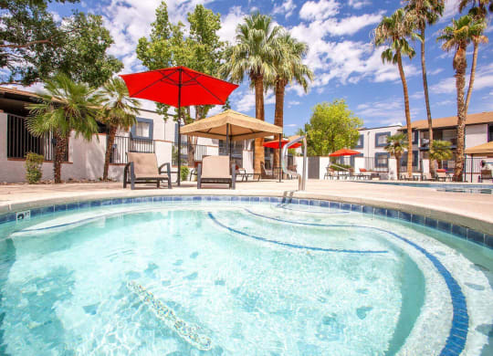 Pet-Friendly Apartments in Tucson, AZ - Peaks at Redington - Soothing Spa Surrounded By Lounge Chairs, Umbrellas, Palm Trees Next to the Swimming Pool
