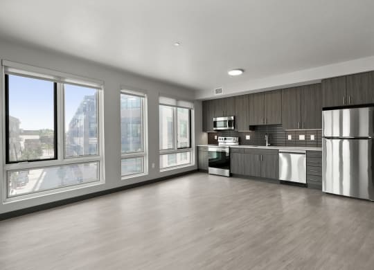 an empty room with a large window and a stainless steel refrigerator