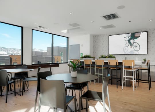 a room with tables and chairs and a projection screen on the wall