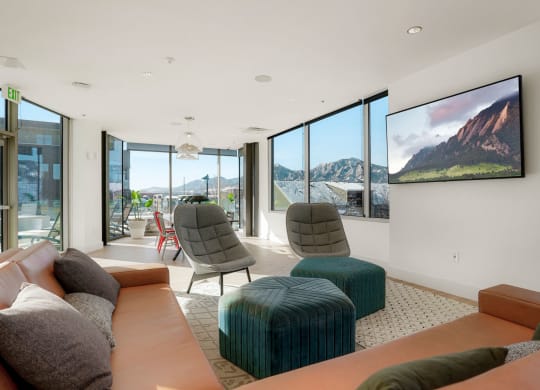 a living room with orange couches and green chairs with a large tv on the wall