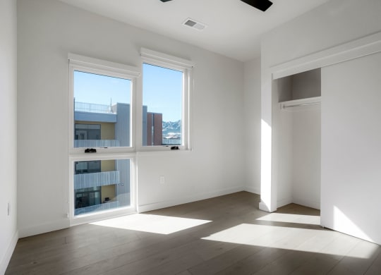 a bedroom with three large windows and a door that leads to a balcony