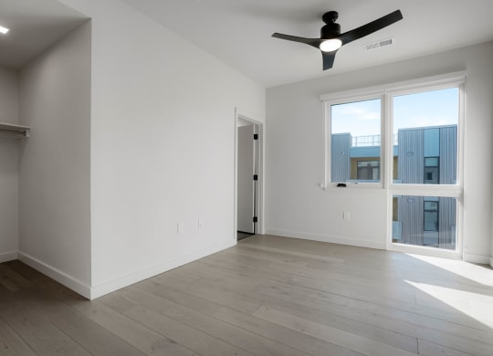 a bedroom with a large window and a ceiling fan