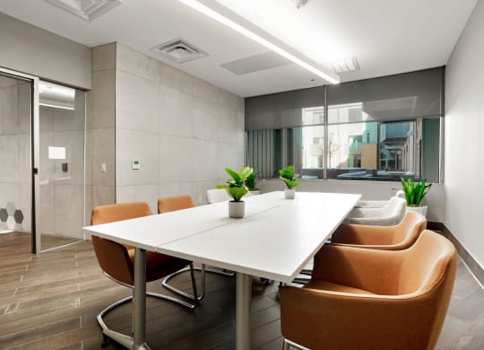 a meeting room with a white table and orange chairs