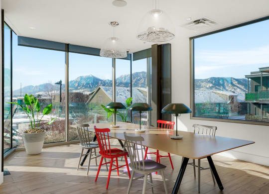 a dining room with a table and chairs with a view of the mountains in the distance