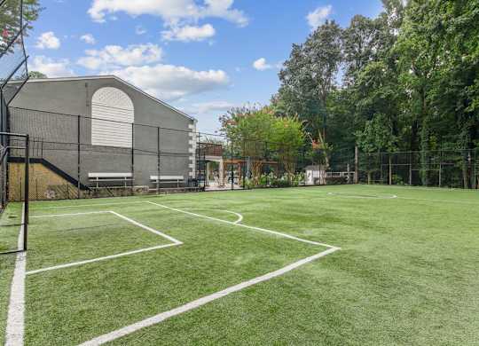 A tennis court surrounded by a fence and trees.