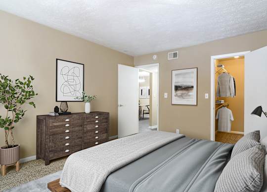 A bedroom with a large bed and a dresser with a plant on top.