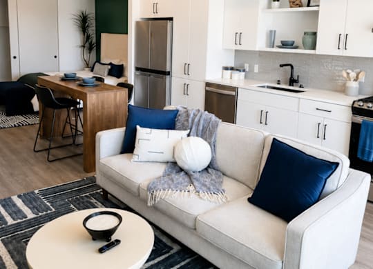 A modern living room with a white couch and a round ottoman.