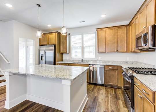Apartments In Charleston, SC - Sumner Village - Kitchen With Vinyl Plank Flooring, Stainless Steel Appliances, Granite Countertops, Spacious Island, Large Window, And Wooden Cabinets