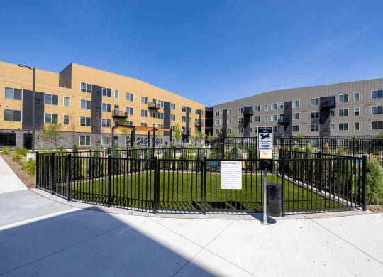a fenced in grassy area in front of an apartment building