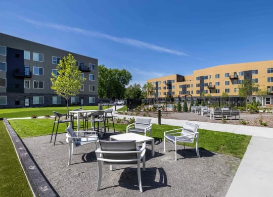 a courtyard with tables and chairs in front of an apartment building