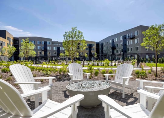 an outdoor patio with white chairs and a fire pit