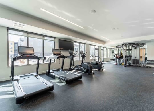 a gym with cardio equipment and windows in a building