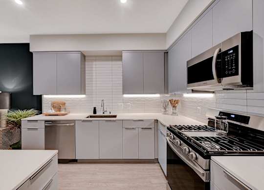 A modern kitchen with a black countertop and white cabinets.
