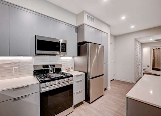 A modern kitchen with stainless steel appliances and white countertops.