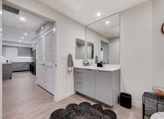 A bathroom with a vanity, mirror, and a rug.