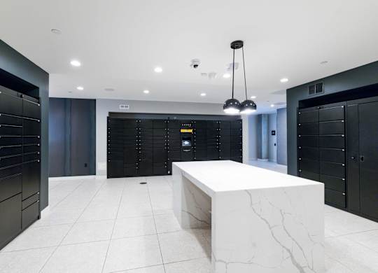 A white marble table is in the middle of a room with black lockers on the walls.
