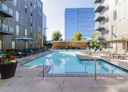 A pool surrounded by chairs and buildings.