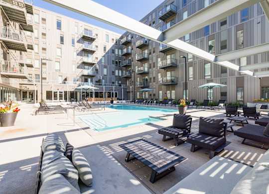 A large outdoor pool area with lounge chairs and umbrellas.