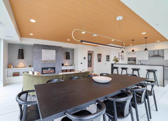 A modern kitchen with a wooden ceiling and a dining table with chairs.