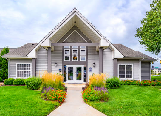 the front of leasing office with a green lawn and colorful flowers