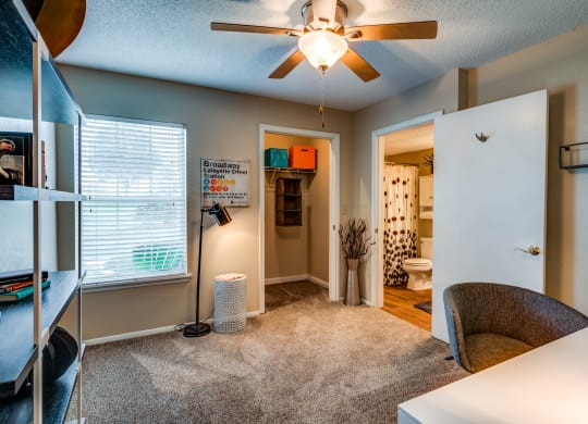 a bedroom with a ceiling fan and a desk with a chair