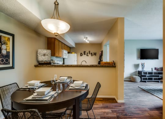 a dining area with a table and chairs and a kitchen in the background