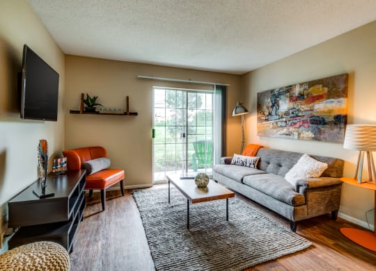 a living room with a couch and chair and a tv on the wall