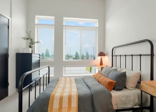 1-BR Apartments in Wheat Ridge, CO - Parallel - Bedroom with Plush Capreting, Bed, Nightstand, Dresser, and Large Window.