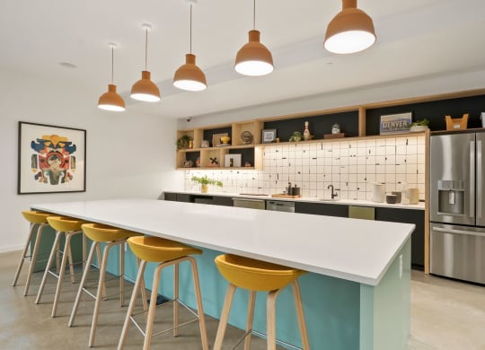 a kitchen with a long white counter and yellow and blue stools